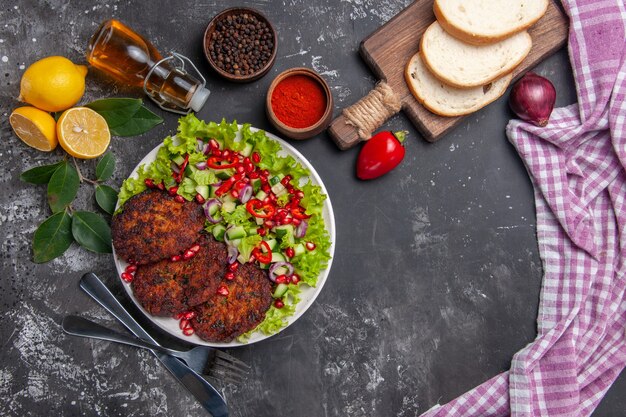 Vista superior de chuletas de carne con ensalada y pan