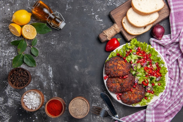 Vista superior de chuletas de carne con ensalada y pan