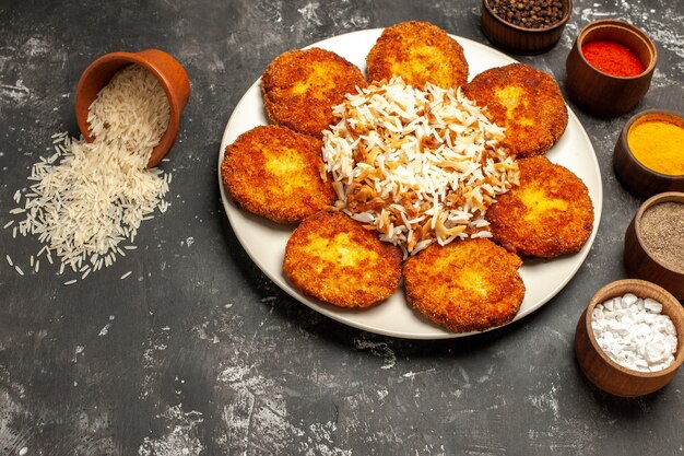 Vista superior de chuletas fritas con arroz cocido y condimentos en una superficie oscura plato de carne de comida fotográfica