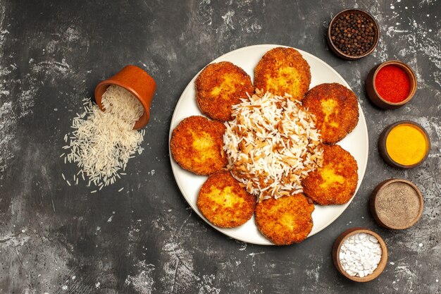 Vista superior de chuletas fritas con arroz cocido y condimentos en una superficie oscura plato de carne de comida fotográfica