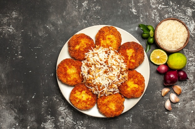 Vista superior chuletas fritas con arroz cocido en un escritorio oscuro plato de comida rissole de carne