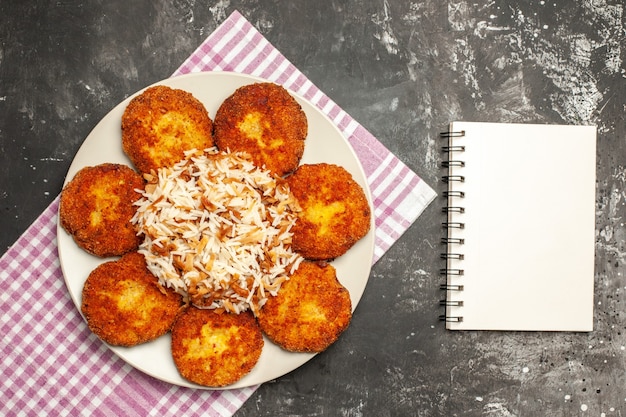 Foto gratuita vista superior de chuletas fritas con arroz cocido en un plato de comida de carne de piso oscuro rissole