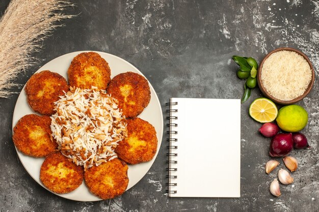 Vista superior chuletas fritas con arroz cocido en la superficie oscura plato de comida rissole de carne