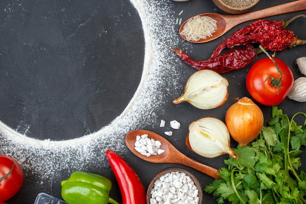 Vista superior círculo de harina espolvoreada tomates cebollas arroz en cuchara de madera cilantro en el espacio libre de la mesa