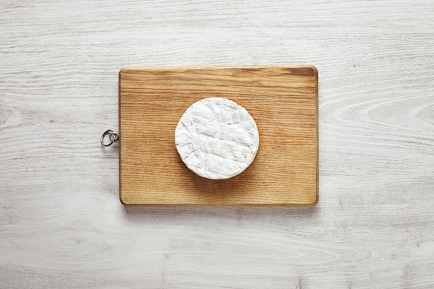 Vista superior del círculo perfecto de queso camembert sobre tabla de madera rústica aislado en madera blanca envejecida