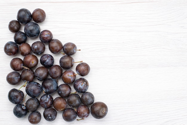 Vista superior ciruelas azules redondas formadas sobre el fondo claro fruta suave amarga jugosa