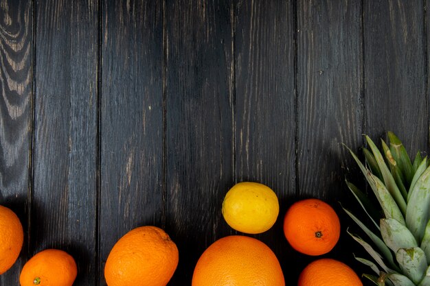 Vista superior de cítricos como mandarina pomelo limón piña sobre fondo de madera con espacio de copia