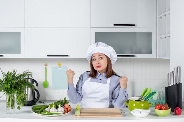 Vista superior de la cocinera confundida y verduras frescas con equipo de cocina y en la cocina blanca