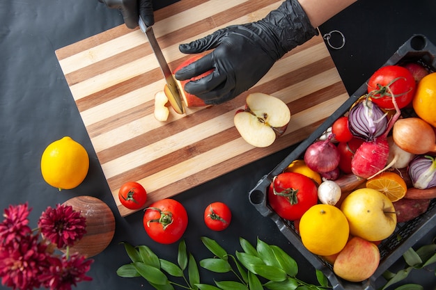 Vista superior cocinera cortando manzana en la superficie oscura