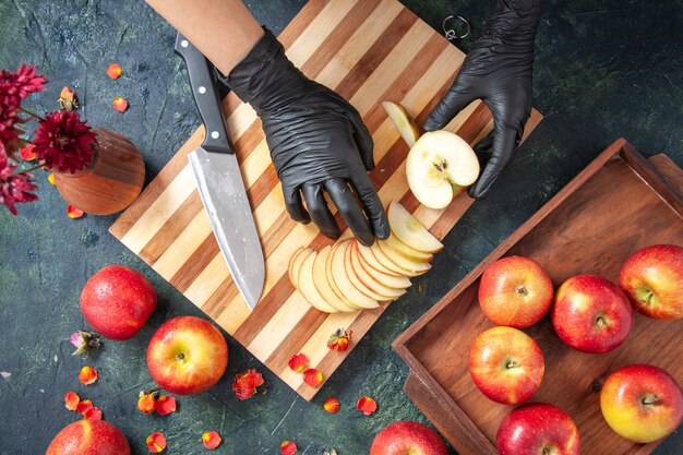 Vista superior cocinera cortando manzanas en la superficie gris