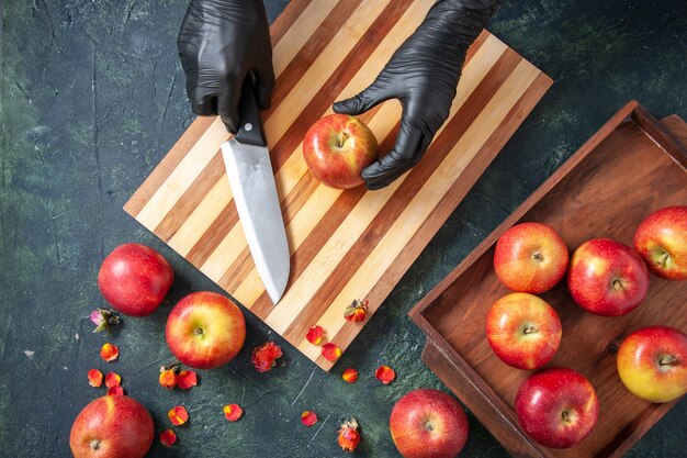 Vista superior cocinera preparándose para cortar manzanas sobre una superficie oscura