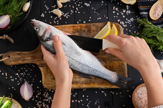 Foto gratuita vista superior cocinero limpiando pescado en la cocina