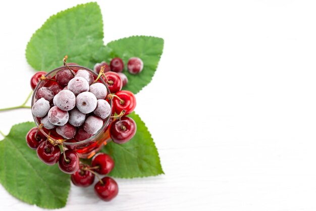 Una vista superior de cóctel de frutas frescas con cerezas rojas frescas enfriamiento con hielo en blanco, cóctel de jugo de bebida color de fruta