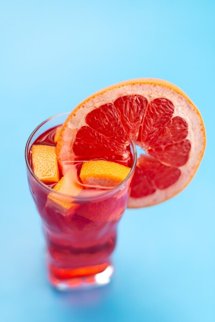 Una vista superior de cóctel de frutas frescas con rodajas de fruta fresca enfriamiento con hielo en azul, cóctel de jugo de bebida color de fruta