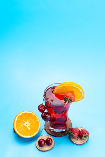 Una vista superior de cóctel de frutas frescas con rodajas de fruta fresca enfriamiento con hielo en azul, cóctel de jugo de bebida color de fruta