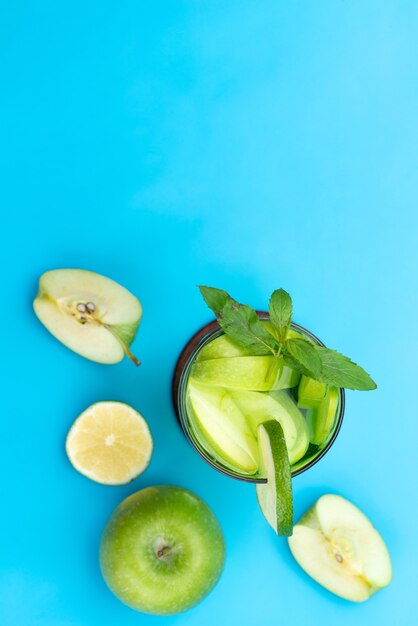 Una vista superior de cóctel de frutas frescas con rodajas de fruta fresca enfriamiento con hielo en azul, cóctel de jugo de bebida color de fruta