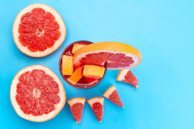 Una vista superior de cóctel de frutas frescas con rodajas de fruta fresca enfriamiento con hielo en azul, cóctel de jugo de bebida color de fruta