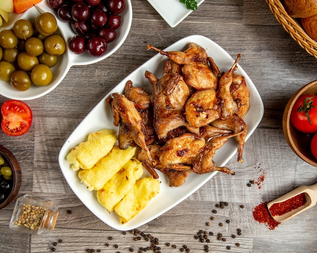 Vista superior de codorniz a la parrilla con lula kebab de papas servidas con pepinillos en la mesa