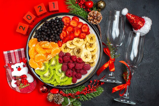 Vista superior de la colección de frutas frescas calcetín de navidad sombrero de sant laus números glaus copas sobre fondo oscuro