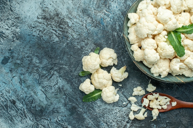 Foto gratuita vista superior de la coliflor fresca dentro de la placa en la mesa gris claro