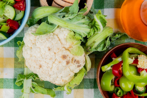 Vista superior de coliflor con pimientos en rodajas y ensalada de verduras con mantequilla derretida sobre tela escocesa