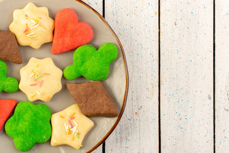 Foto gratuito vista superior de coloridas deliciosas galletas diferentes formadas dentro de la placa redonda en el escritorio de madera gris