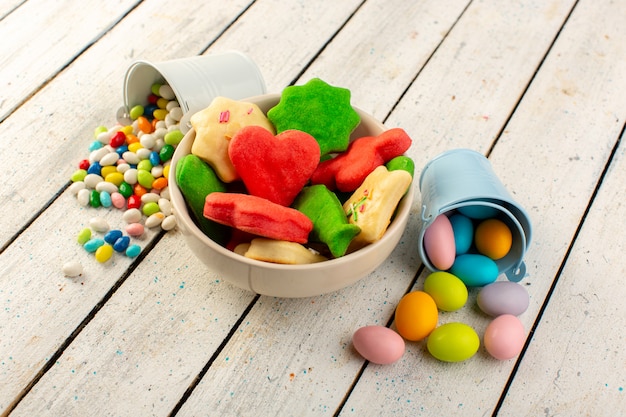 Vista superior de coloridas deliciosas galletas diferentes formadas placa interior multicolor con dulces en el escritorio gris