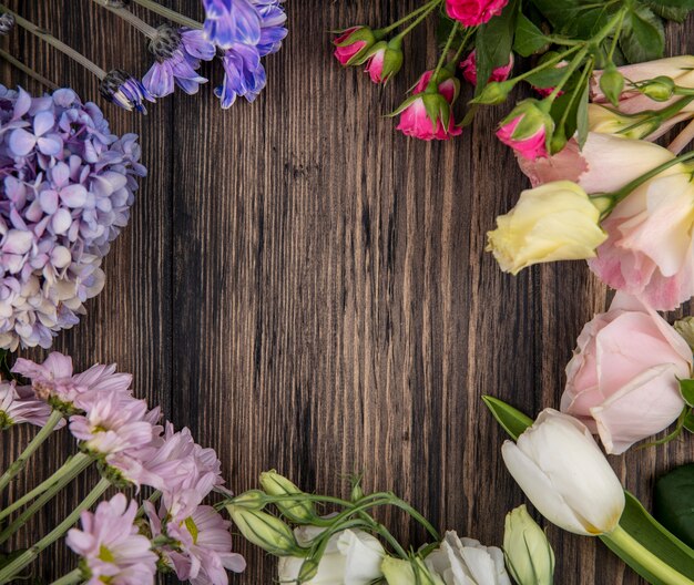 Vista superior de coloridas flores increíbles como margaritas de rosas lilas con hojas sobre un fondo de madera con espacio de copia