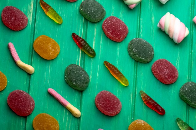 Vista superior de coloridos caramelos de mermelada de gelatina en madera verde