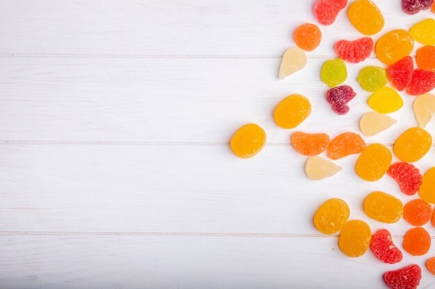 Vista superior de coloridos dulces sabrosos mermelada esparcidos en rústico