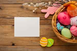 Foto gratuita vista superior de coloridos huevos de pascua en canasta con conejito y papel