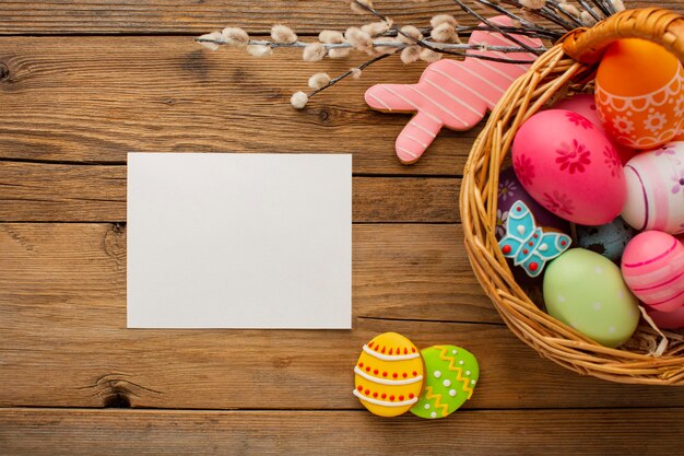 Vista superior de coloridos huevos de pascua en canasta con conejito y papel