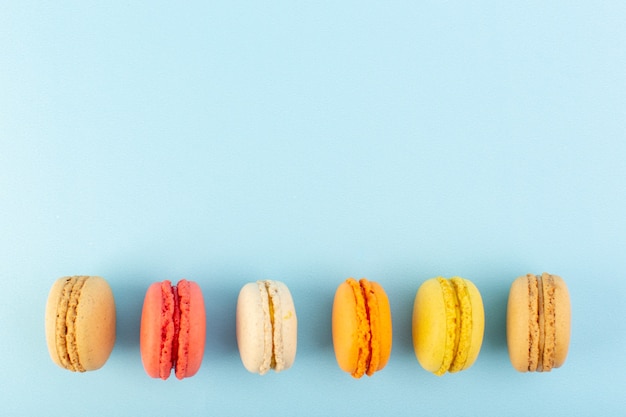 Una vista superior de coloridos macarons franceses deliciosos y horneados en la mesa azul