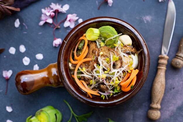 Vista superior de una comida vegana con champiñones, cebollas, zanahorias y puerros