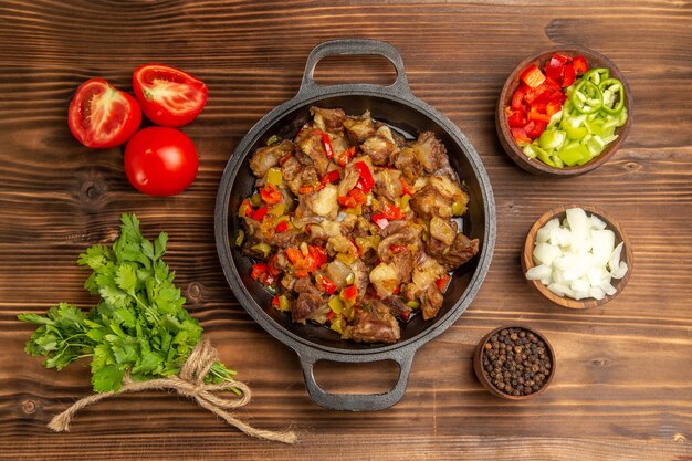 Vista superior comida vegetal cocida con carne y pimiento fresco en rodajas en el escritorio de madera marrón