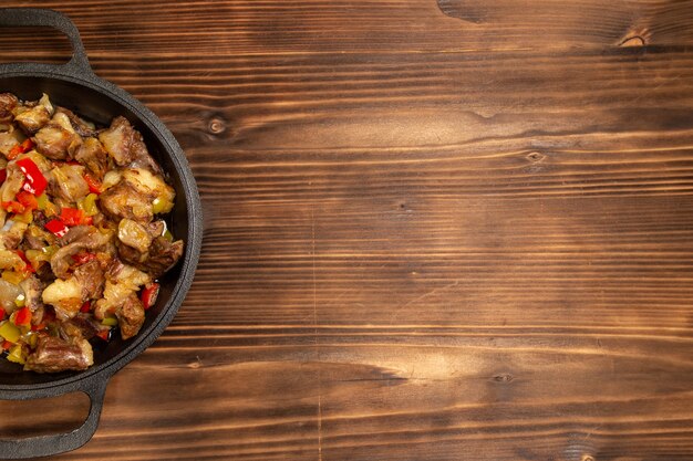 Vista superior de comida vegetal cocida con carne y pimientos en rodajas en el escritorio de madera