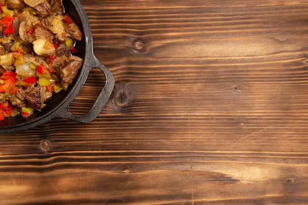 Vista superior de comida vegetal cocida con carne y pimientos en rodajas en la superficie de madera