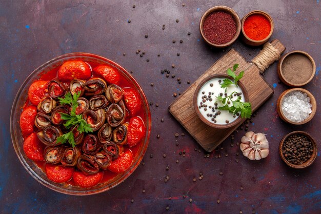 Vista superior de comida vegetal cocida con condimentos y crema agria en la superficie oscura