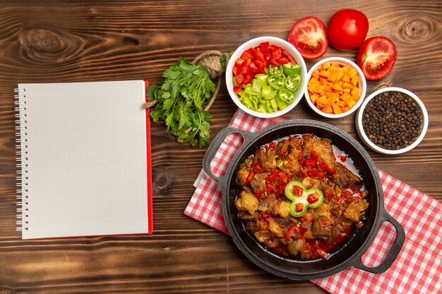 Vista superior de comida vegetal cocida con condimentos en el escritorio marrón