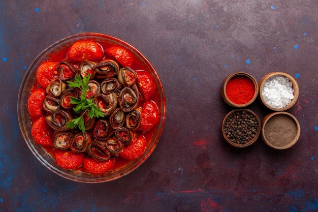 Vista superior comida vegetal cocida deliciosos tomates y berenjenas con condimentos en el piso oscuro cocinando comida plato cena