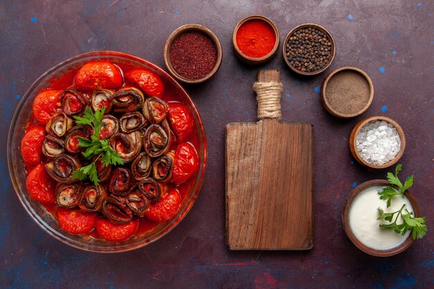 Vista superior comida vegetal cocida deliciosos tomates y berenjenas con condimentos en la superficie oscura