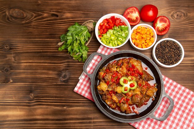 Vista superior de comida vegetal cocida que incluye salsa de verduras y carne en el escritorio marrón