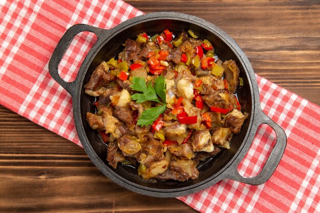 Vista superior de comida vegetal cocida que incluye verduras y carne dentro de un escritorio de madera