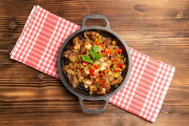 Vista superior de comida vegetal cocida que incluye verduras y carne dentro de un escritorio marrón de madera