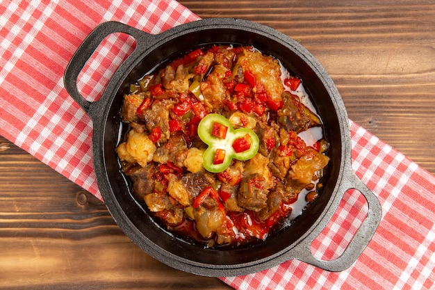 Vista superior de comida vegetal cocida que incluye verduras y carne dentro de un escritorio marrón de madera