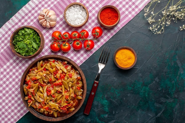 Vista superior comida vegetal en rodajas deliciosa comida con frijoles dentro de una olla marrón sobre fondo azul.