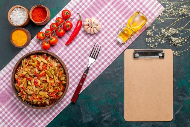 Vista superior de comida vegetal en rodajas con diferentes condimentos en el escritorio azul