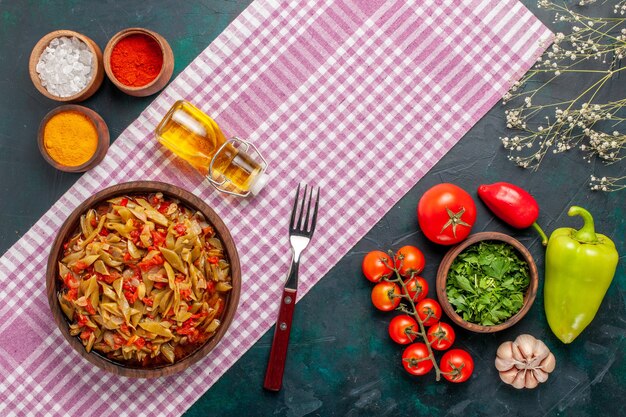 Vista superior de comida vegetal en rodajas con diferentes condimentos sobre fondo azul oscuro