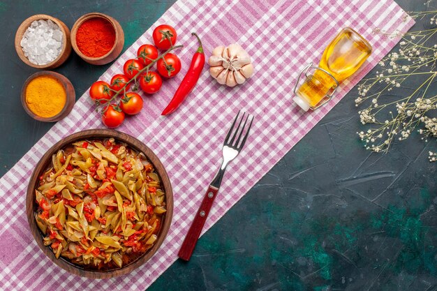 Vista superior de comida vegetal en rodajas con diferentes condimentos sobre el fondo azul.