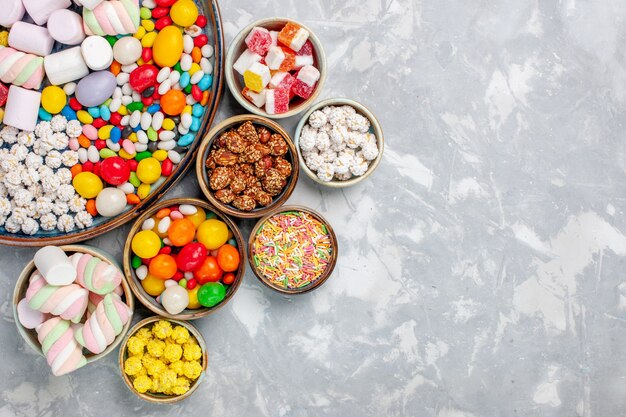 Vista superior de composición de caramelos dulces y deliciosos caramelos con malvavisco en el escritorio blanco azúcar golosina confitura dulce